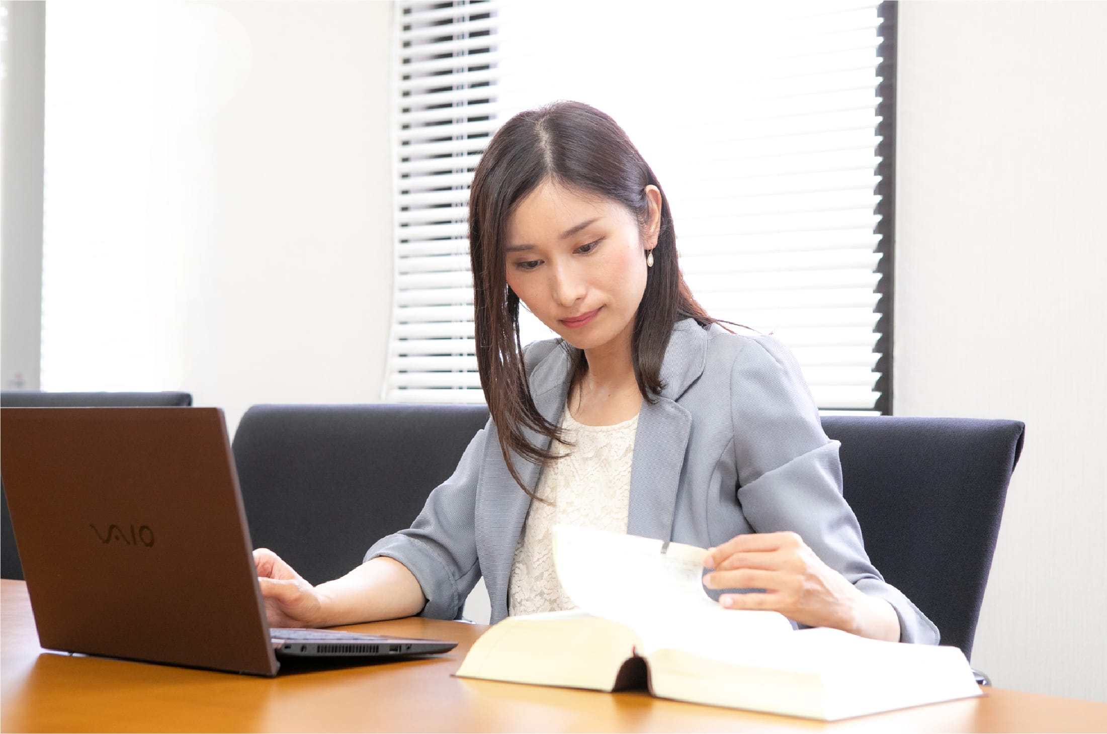 机で資料を確認しているスーツ姿の上春奈津美弁護士